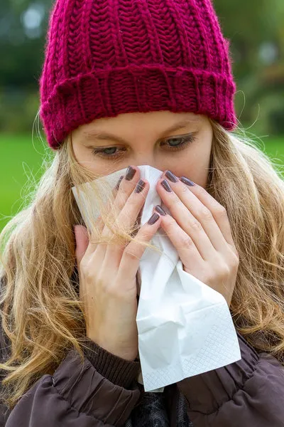 Sick woman using a tissue outdoors