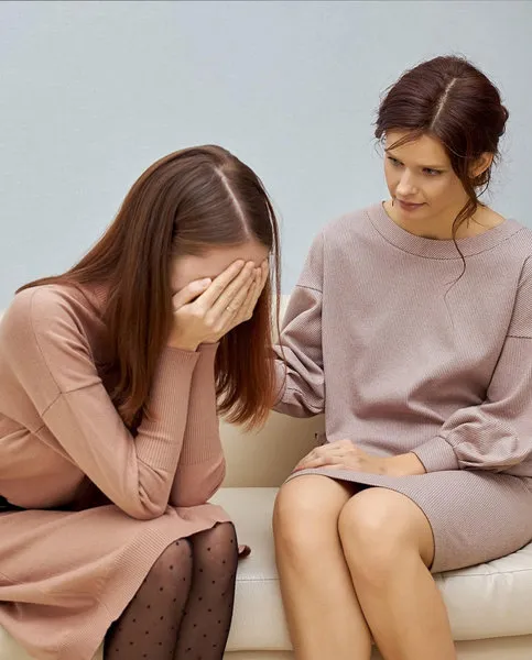 Woman showing emotional distress while receiving support, representing PTSD symptoms.